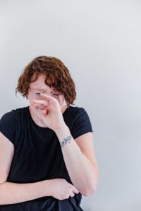 A woman holding her nose and cringing
